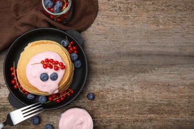 Photo of Tasty pancakes with natural yogurt, blueberries and red currants on wooden table, flat lay. Space for text