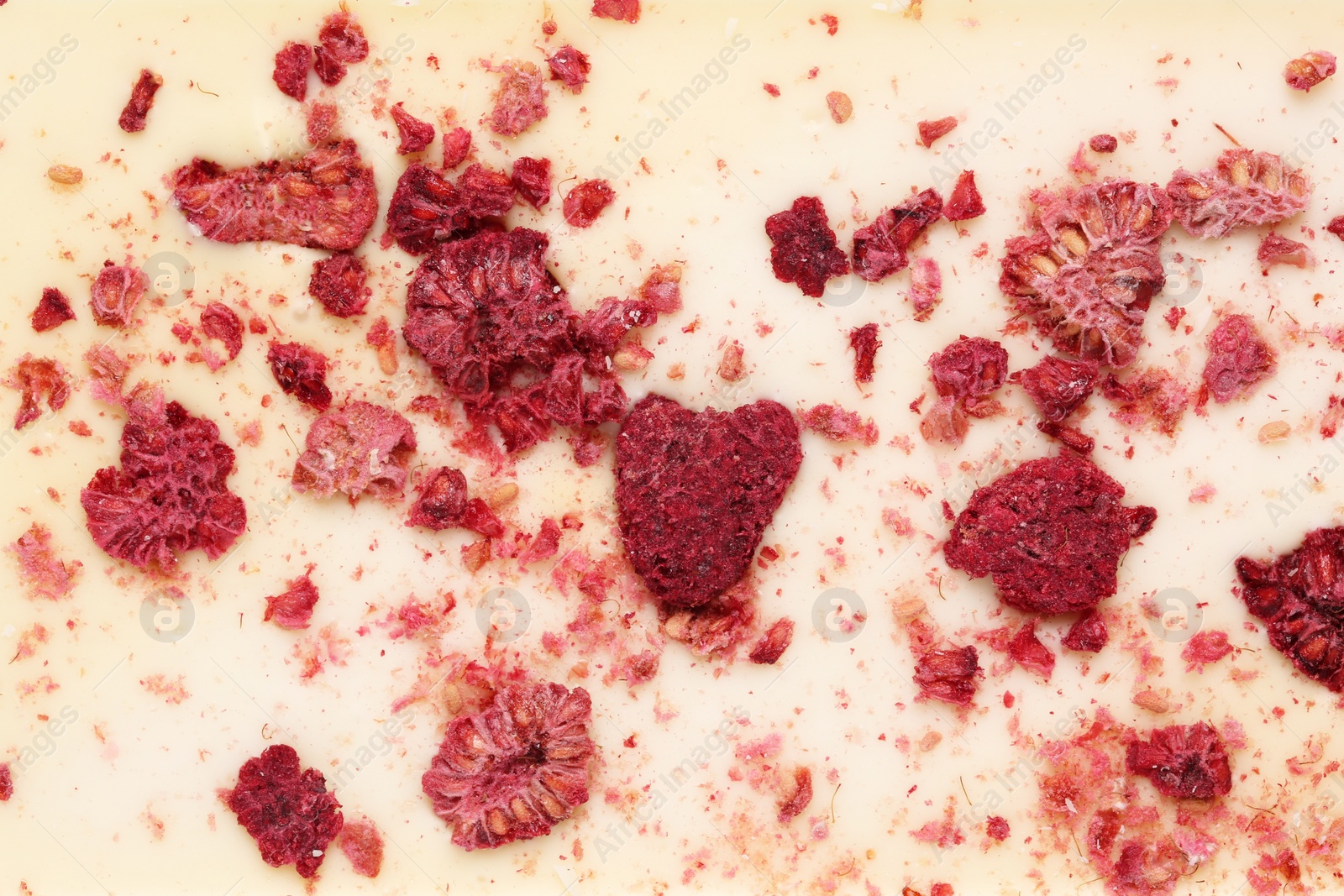 Photo of Chocolate bar with freeze dried raspberries as background, closeup