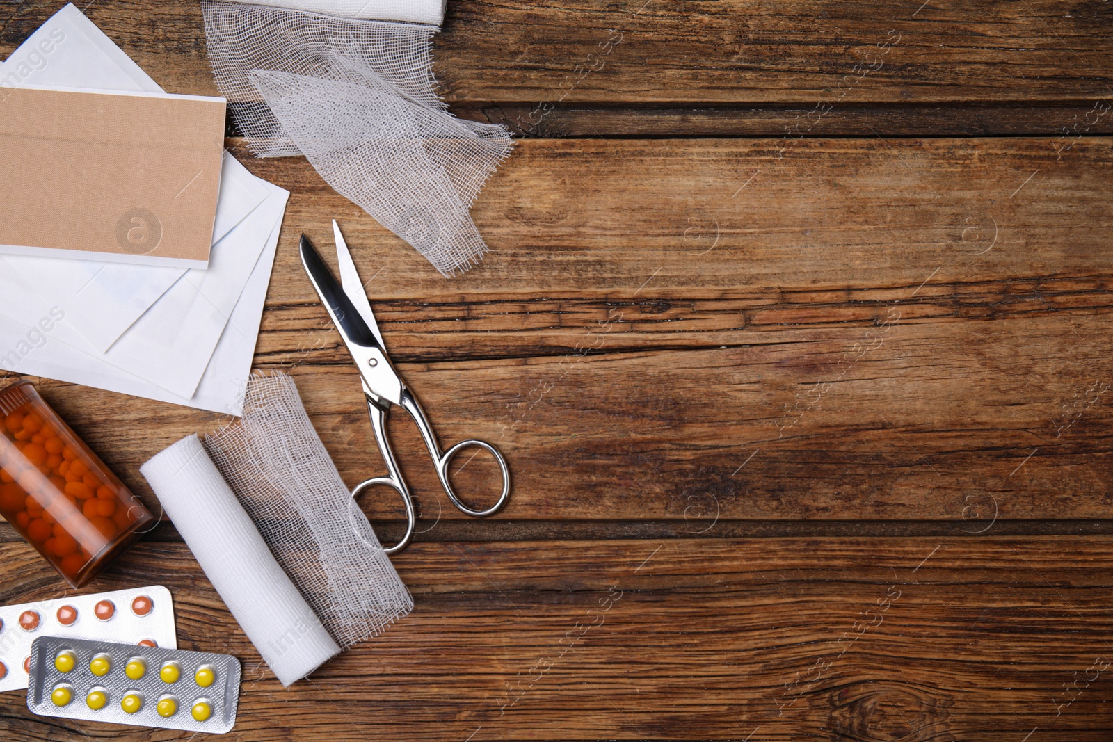 Photo of White bandage rolls and medical supplies on wooden table, flat lay. Space for text