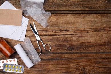 Photo of White bandage rolls and medical supplies on wooden table, flat lay. Space for text