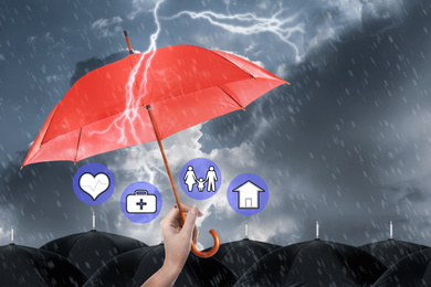 Image of Insurance agent covering illustrations with red umbrella during storm