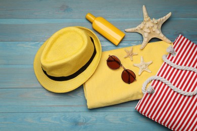 Photo of Stylish bag and beach accessories on blue wooden background, flat lay