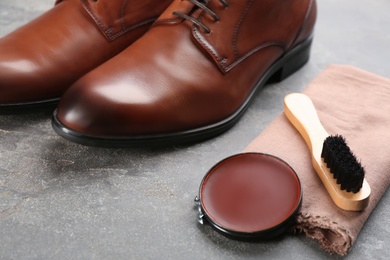 Photo of Shoe care products and footwear on grey stone table, closeup