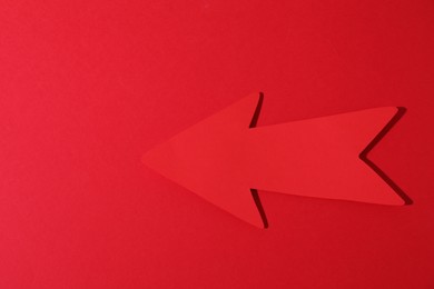 One paper arrow on red background, top view. Space for text