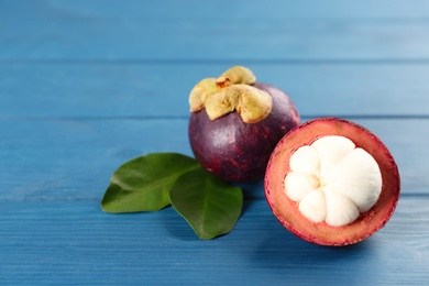 Photo of Delicious tropical mangosteens on blue wooden table