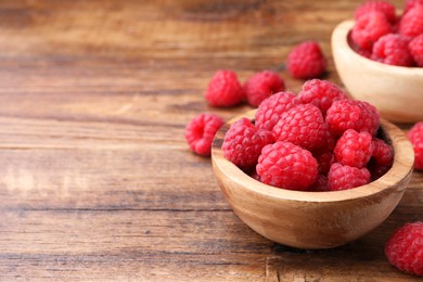 Photo of Tasty ripe raspberries on wooden table, space for text