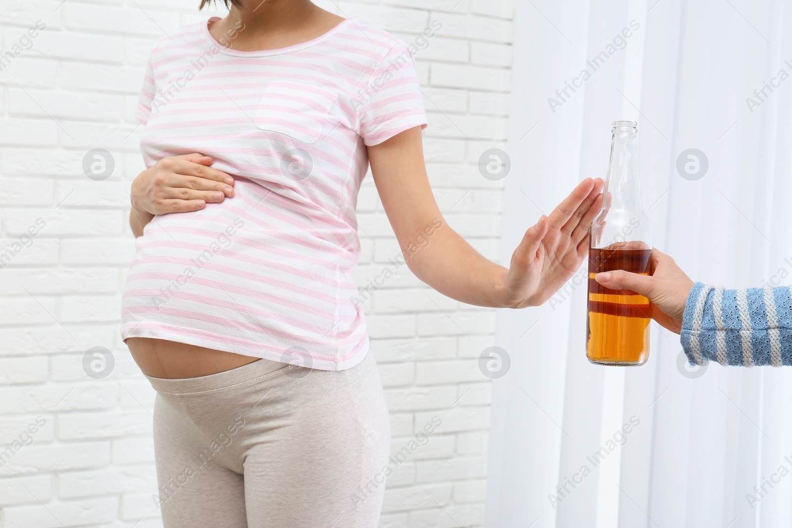 Photo of Pregnant woman declining whiskey indoors. Alcohol harm