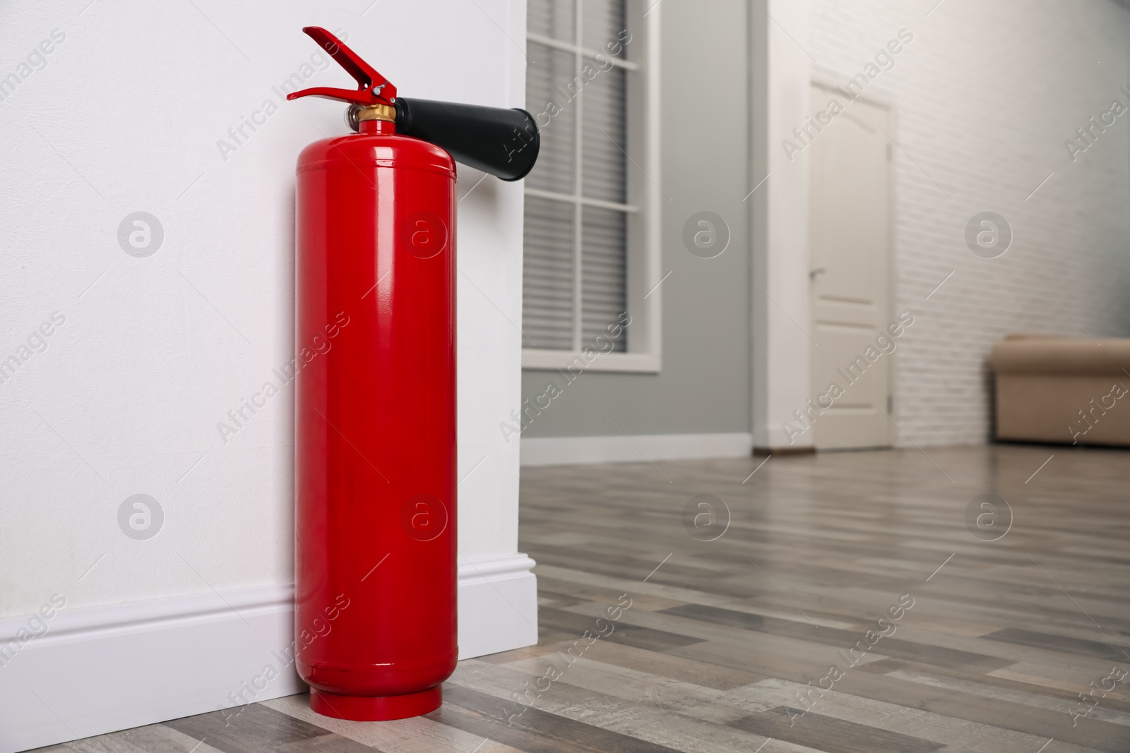 Photo of Fire extinguisher near white wall indoors. Space for text