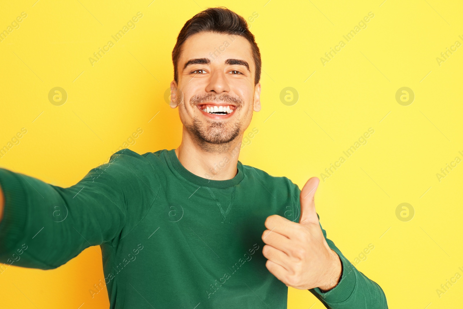 Photo of Young handsome man taking selfie against color background