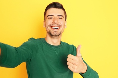 Photo of Young handsome man taking selfie against color background