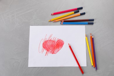 Cute child`s drawing of red heart and colorful pencils on grey table, flat lay