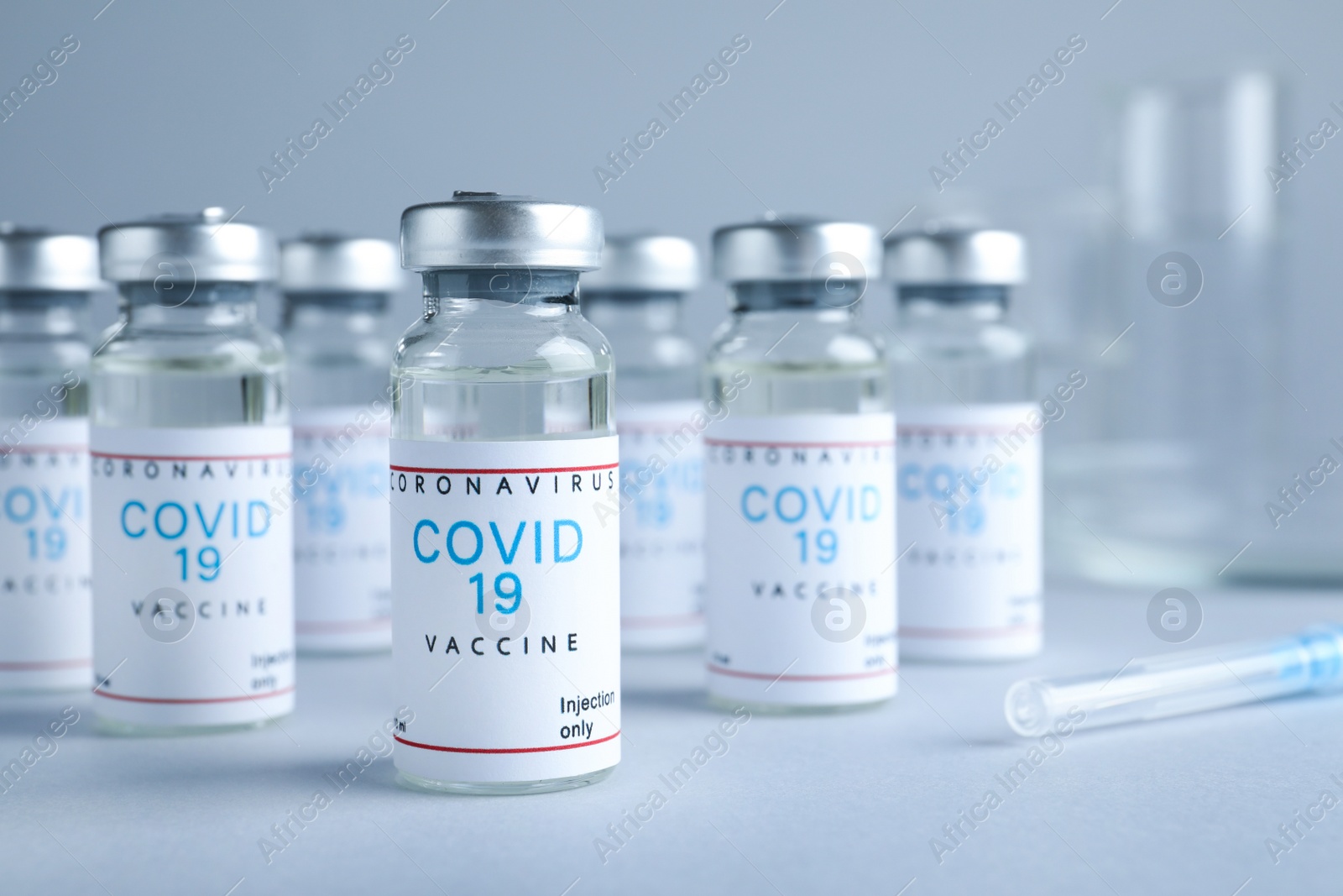 Photo of Vials with coronavirus vaccine on light grey background