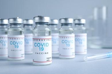 Vials with coronavirus vaccine on light grey background