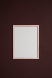 Photo of Empty frame on brown wall. Mockup for design