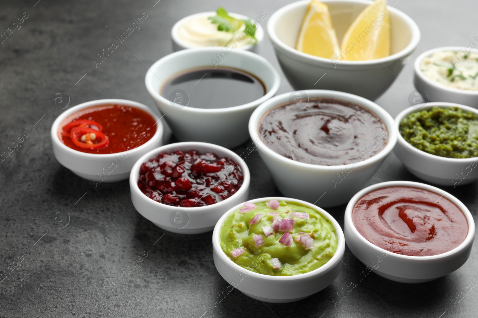 Photo of Different tasty sauces in bowls on grey table, closeup