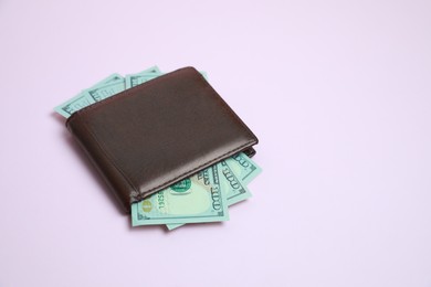 Photo of Stylish brown leather wallet with dollar banknotes on light background. Space for text