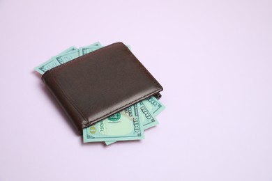 Stylish brown leather wallet with dollar banknotes on light background. Space for text