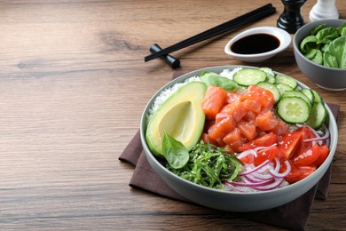 Photo of Delicious poke bowl with salmon and vegetables served on wooden table. space for text