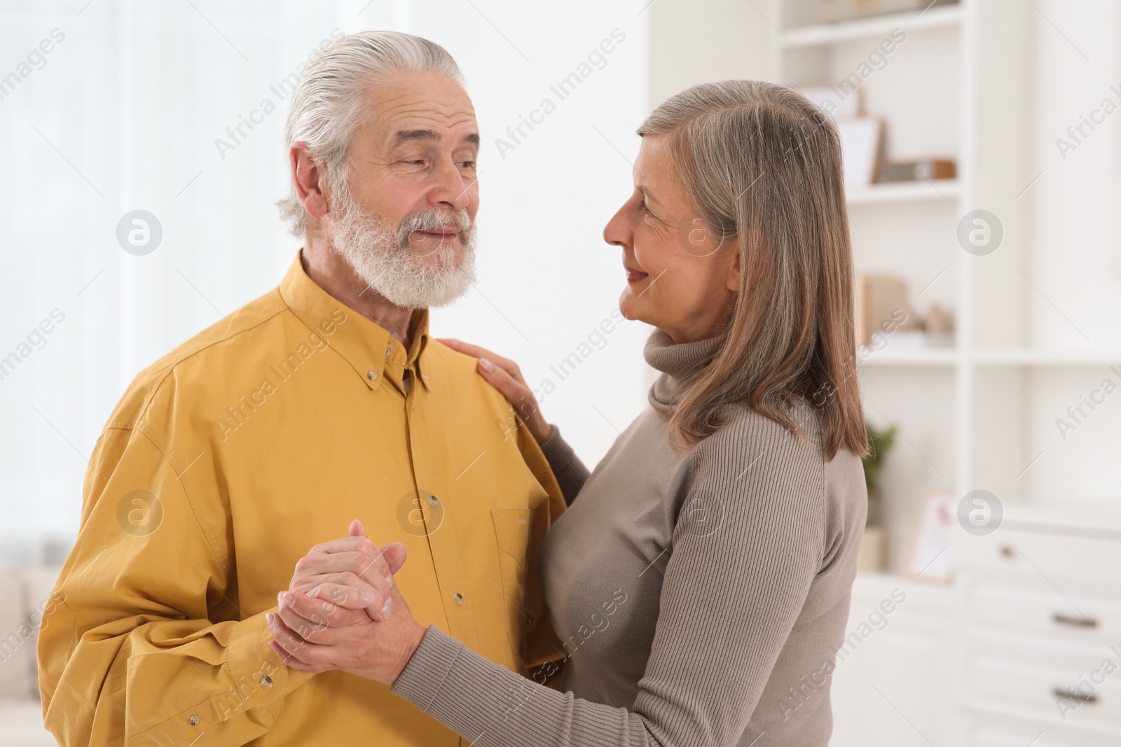 Photo of Affectionate senior couple dancing in living room at home