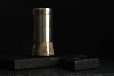 Photo of Pepper shaker on black table. Space for text