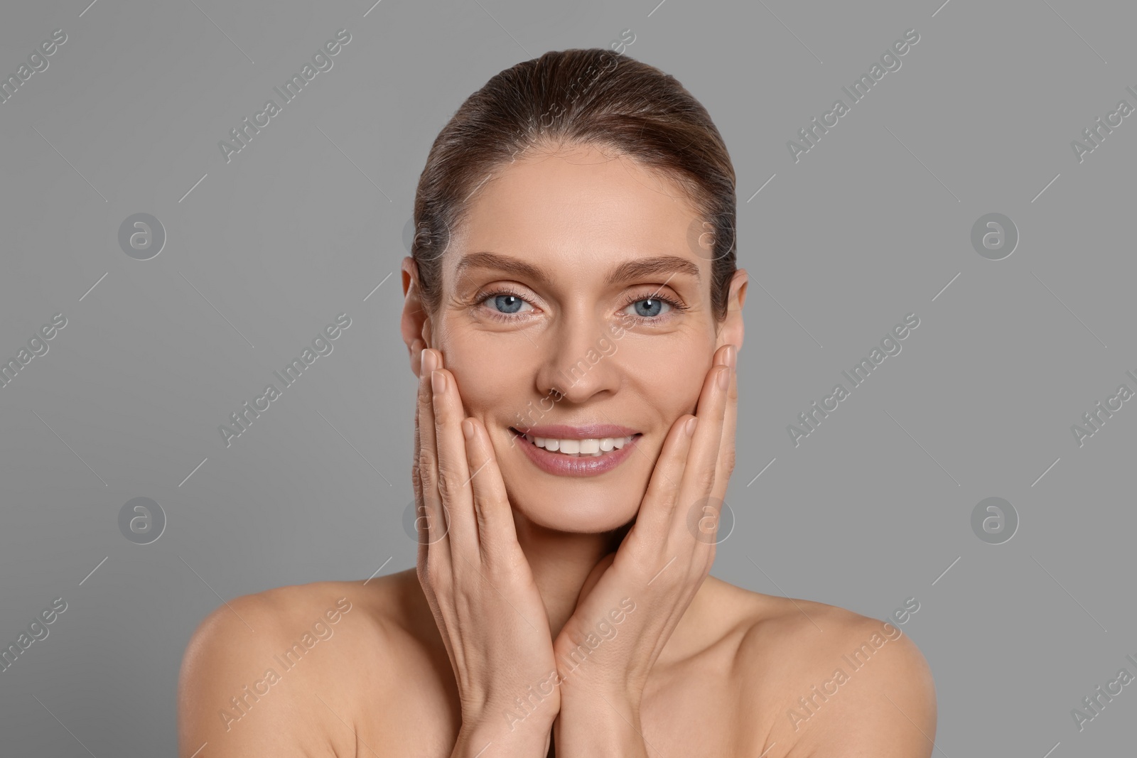 Photo of Woman massaging her face on grey background