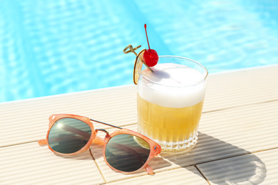 Delicious cocktail and sunglasses near swimming pool. Refreshing drink
