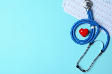 Photo of Stethoscope with red heart and cardiogram on blue background, flat lay. Space for text