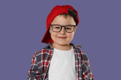 Photo of Cute little boy in glasses on purple background