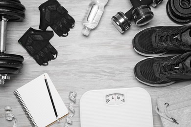 Photo of Notebook, scales and sports equipment on white wooden table, flat lay with space for text. Personal training