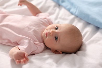 Photo of Cute little baby lying on white sheets