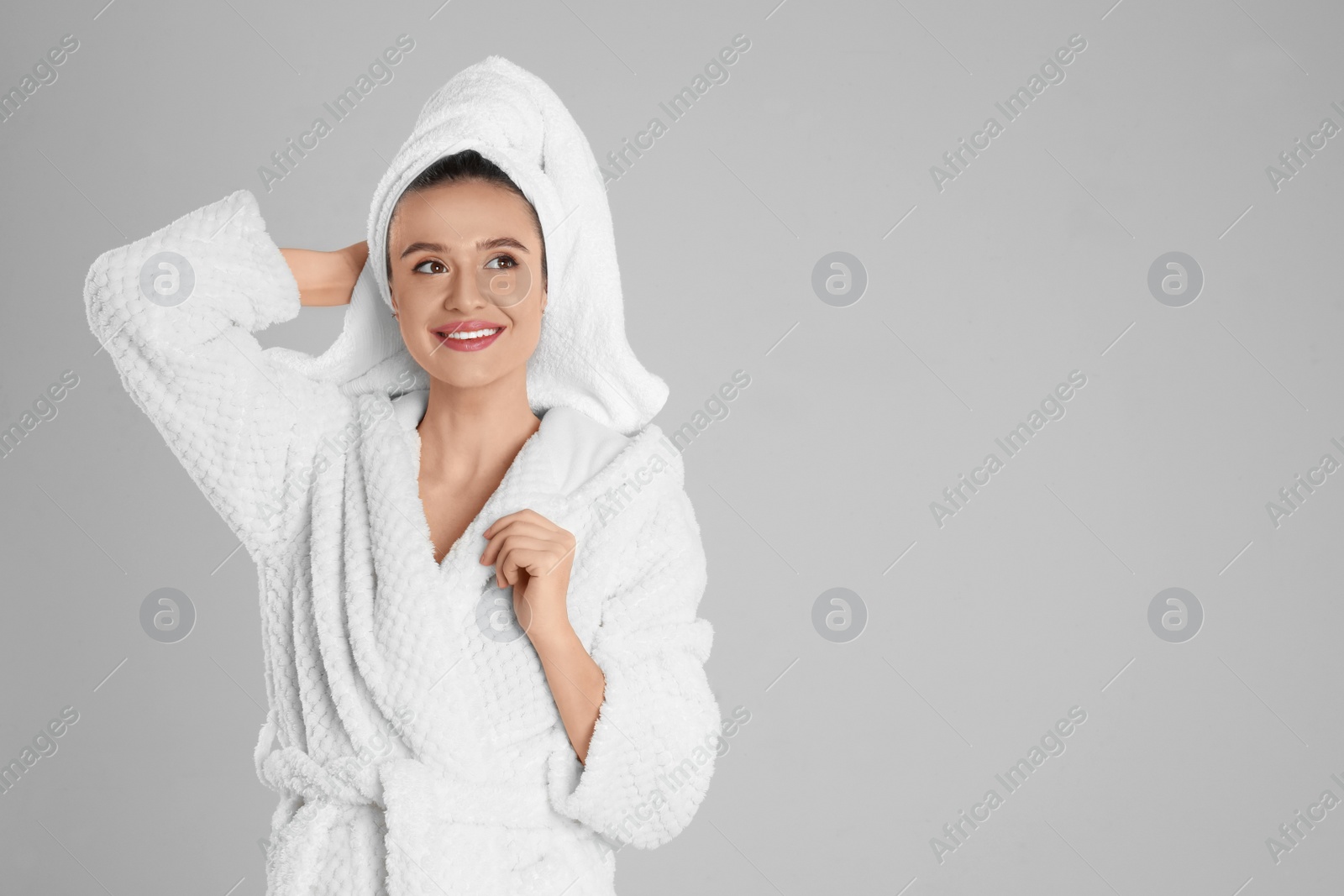 Photo of Beautiful young woman in bathrobe on light grey background. Space for text