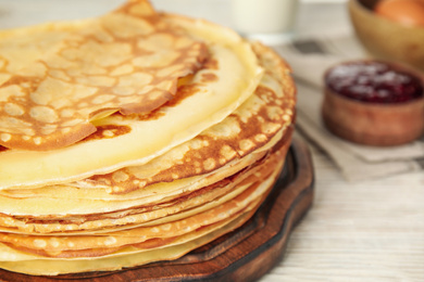 Photo of Fresh thin pancakes on white wooden table, closeup