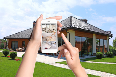 Image of Alarm system. Woman monitoring modern CCTV cameras on smartphone near her house, closeup