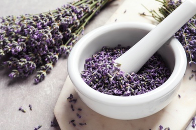 Photo of Mortar and pestle with lavender flowers on grey stone background, space for text. Natural cosmetic