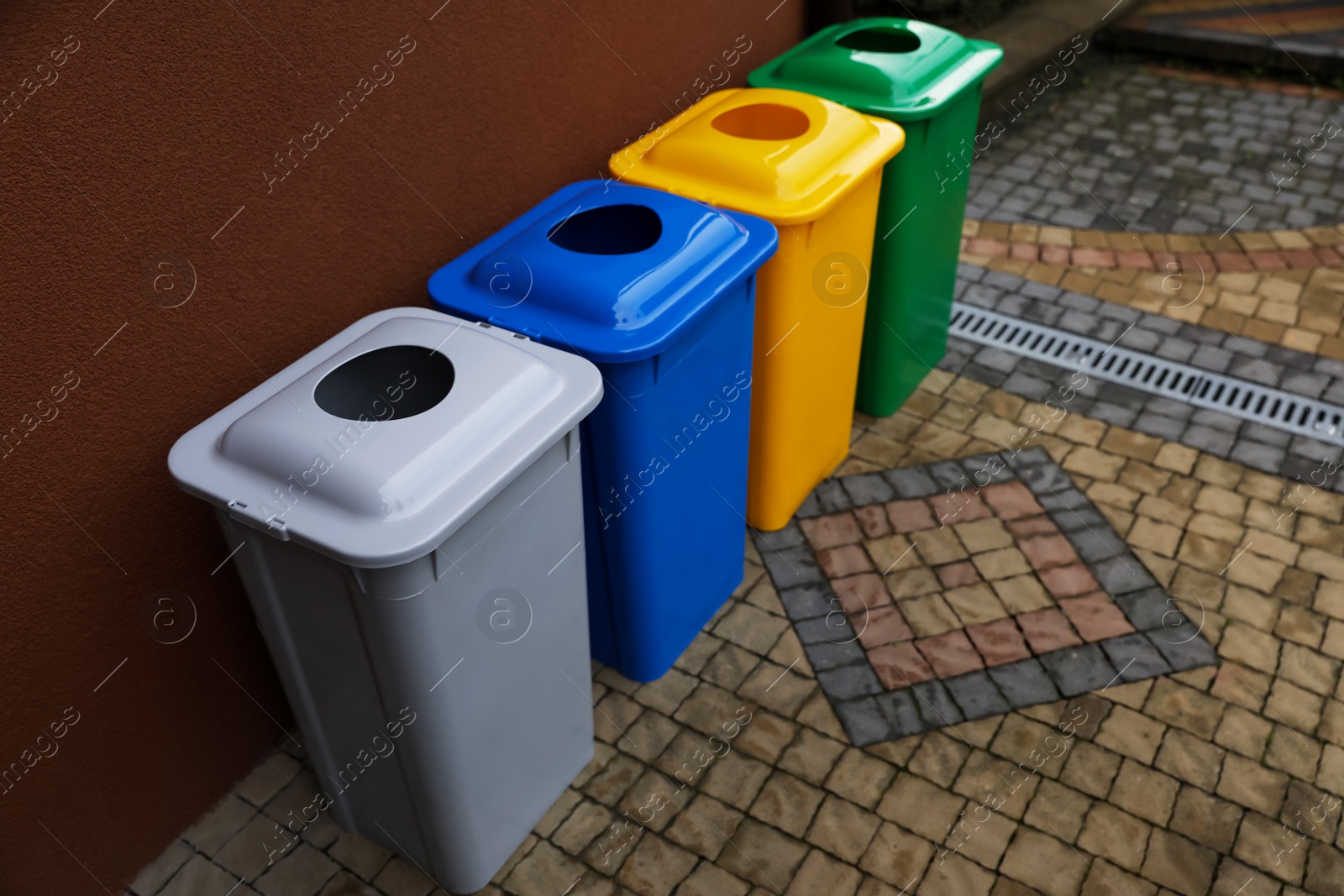 Photo of Many color recycling bins near brown wall outdoors, space for text