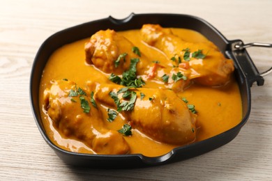 Photo of Tasty chicken curry with parsley on wooden table, closeup