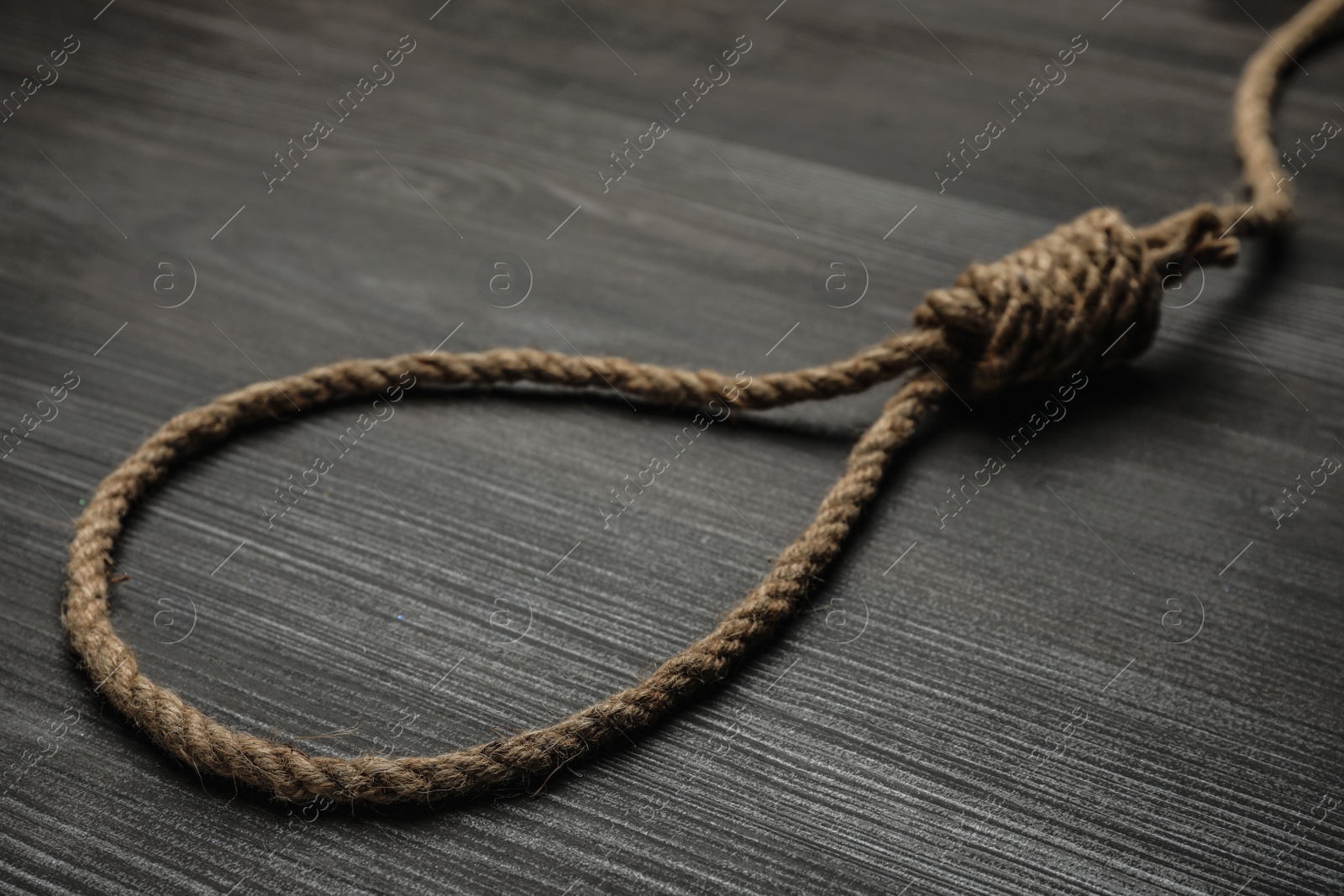 Photo of Rope noose on black wooden table, closeup