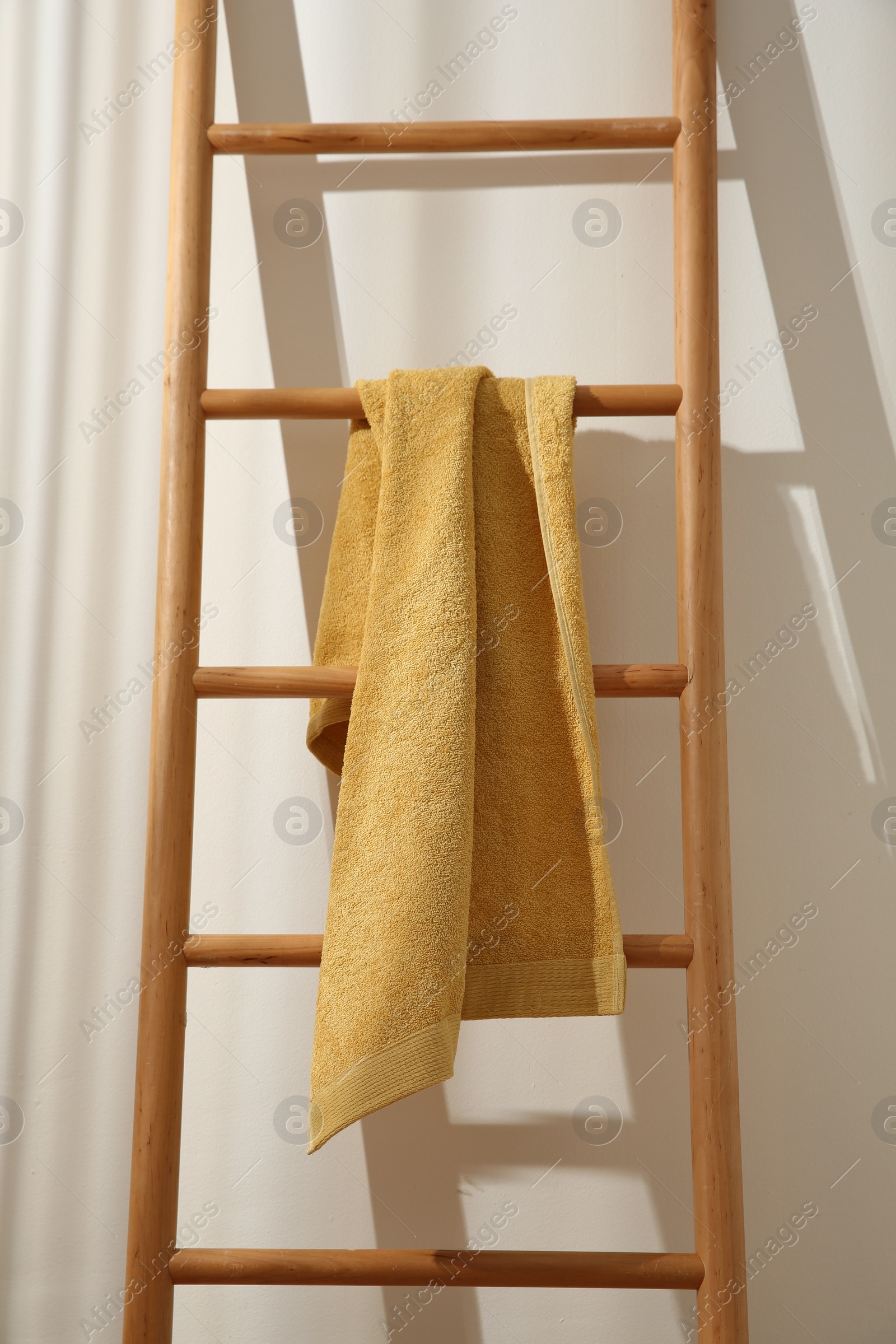 Photo of Yellow towel hanging on wooden ladder indoors