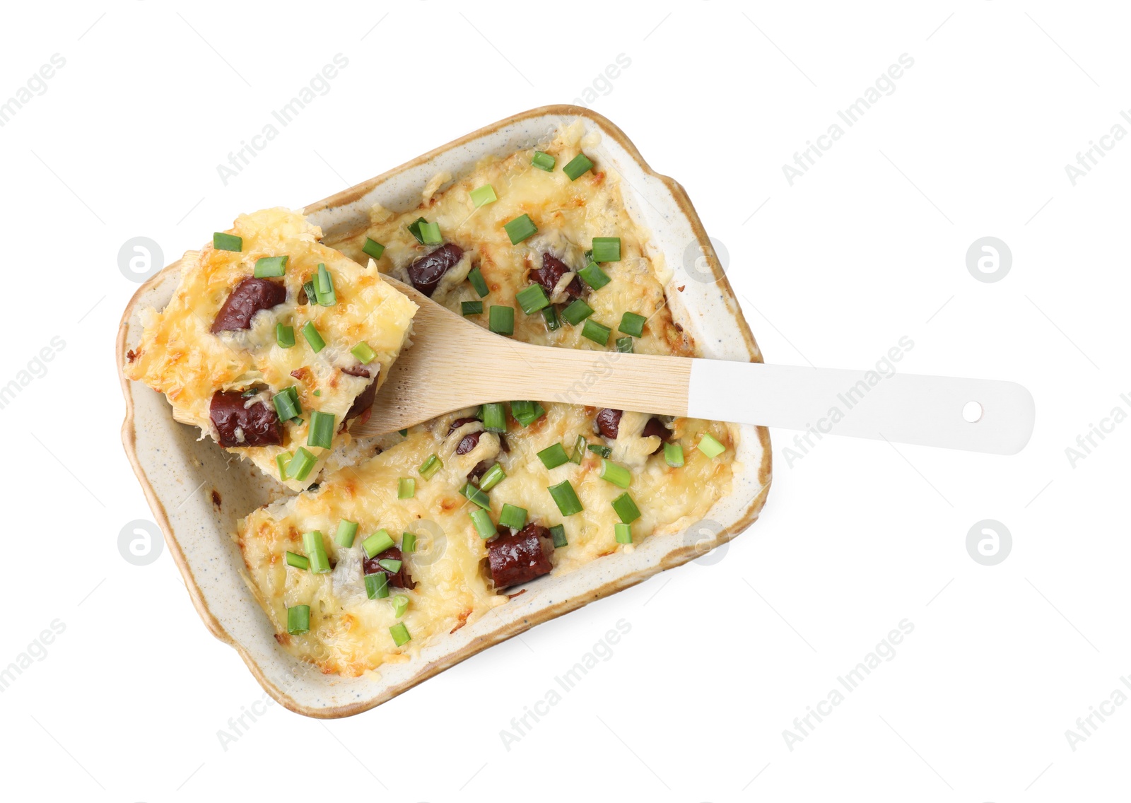 Photo of Taking piece of tasty sausage casserole with green onion from baking dish isolated on white, top view