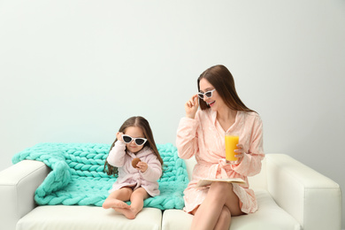 Photo of Mother and daughter in bathrobes sitting on sofa