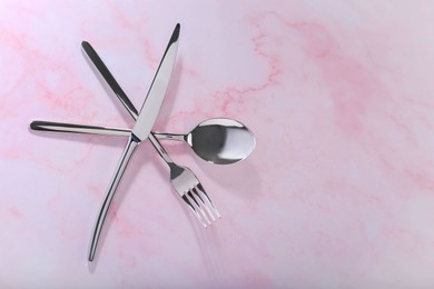 Stylish cutlery set on pink marble table, flat lay. Space for text