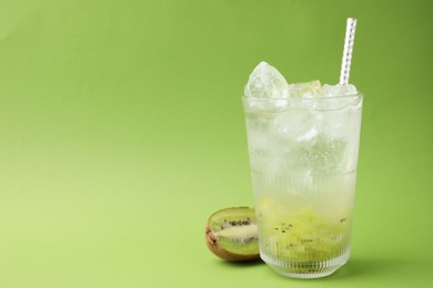 Glass of refreshing drink and cut kiwi on green background, space for text