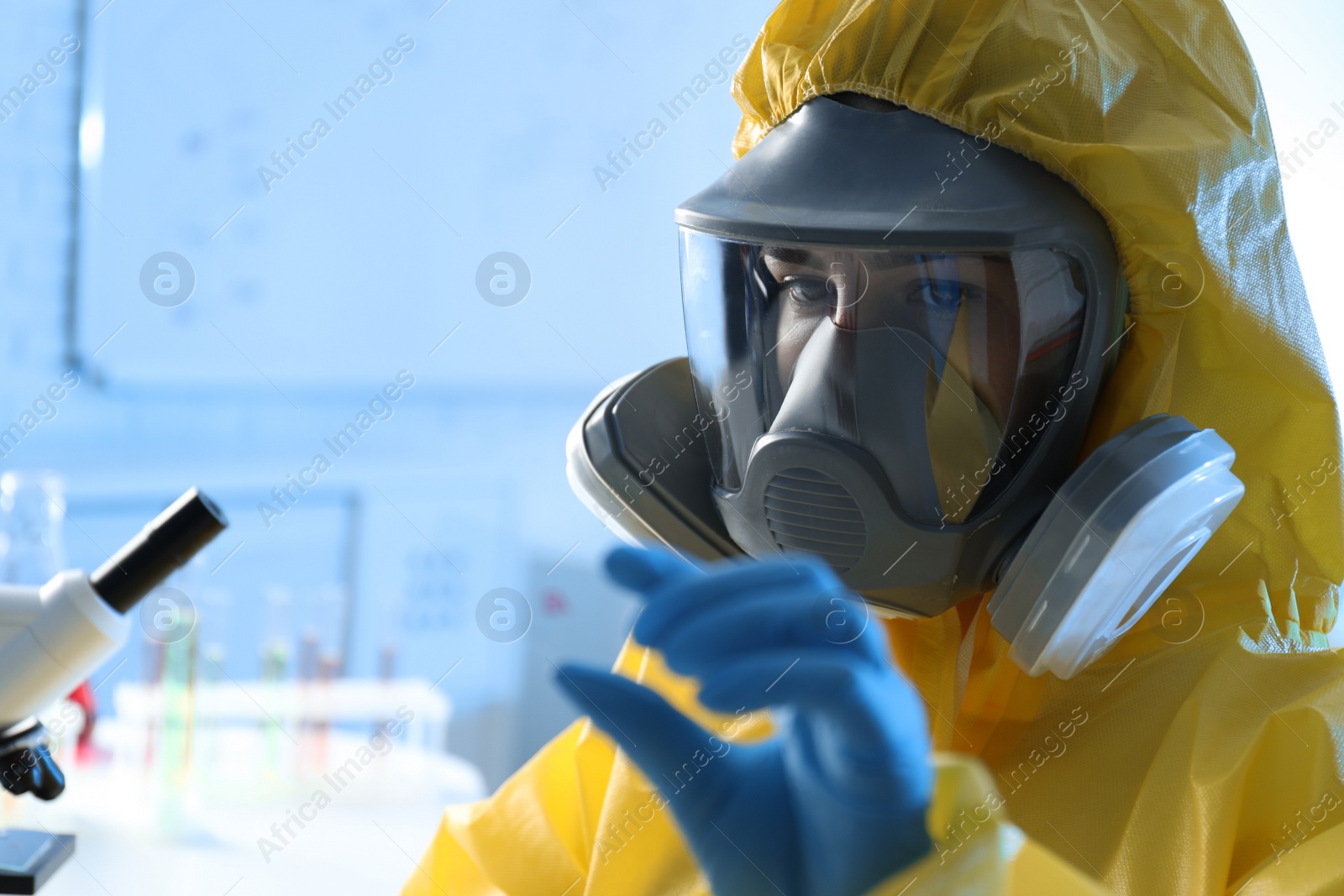 Photo of Scientist in chemical protective suit with microscope slide at laboratory. Virus research