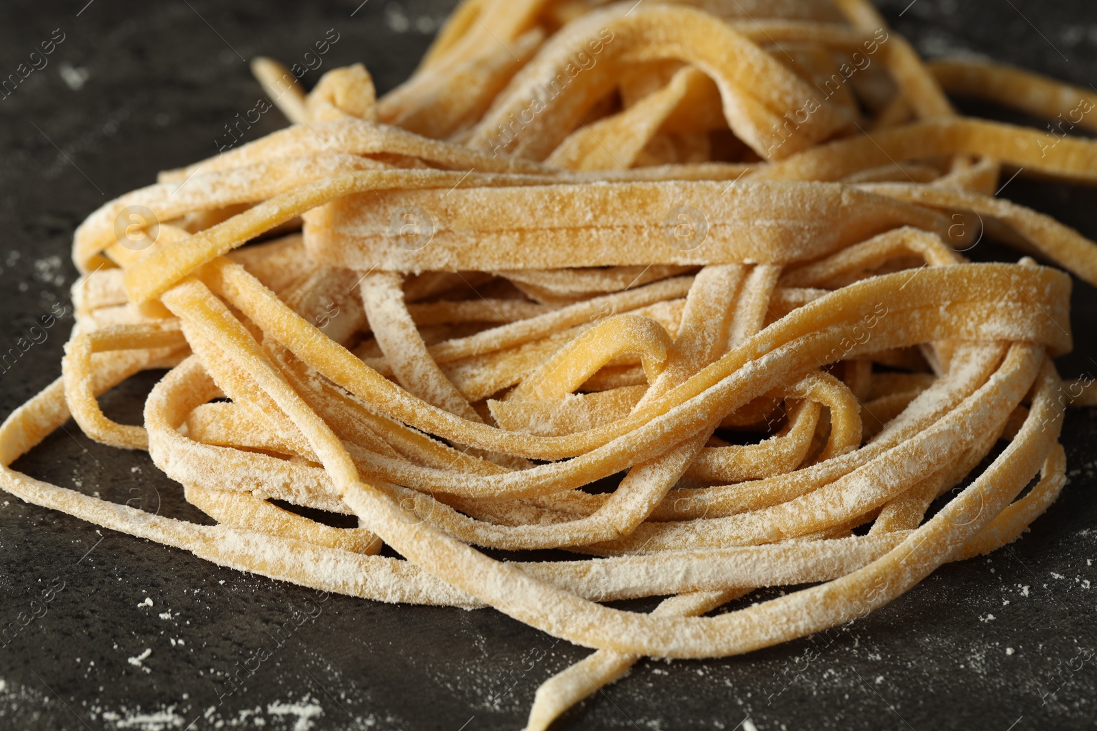 Photo of Uncooked homemade pasta on dark grey table, closeup