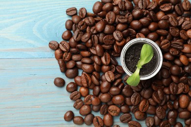 Photo of Coffee capsule with seedling and beans on light blue wooden table, flat lay. Space for text
