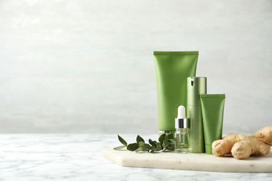 Photo of Set of cosmetic products, ginger and plant on white marble table, space for text