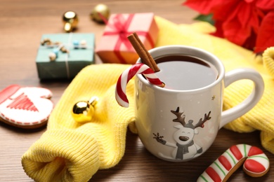 Composition with cup of hot drink and yellow sweater on wooden table, closeup