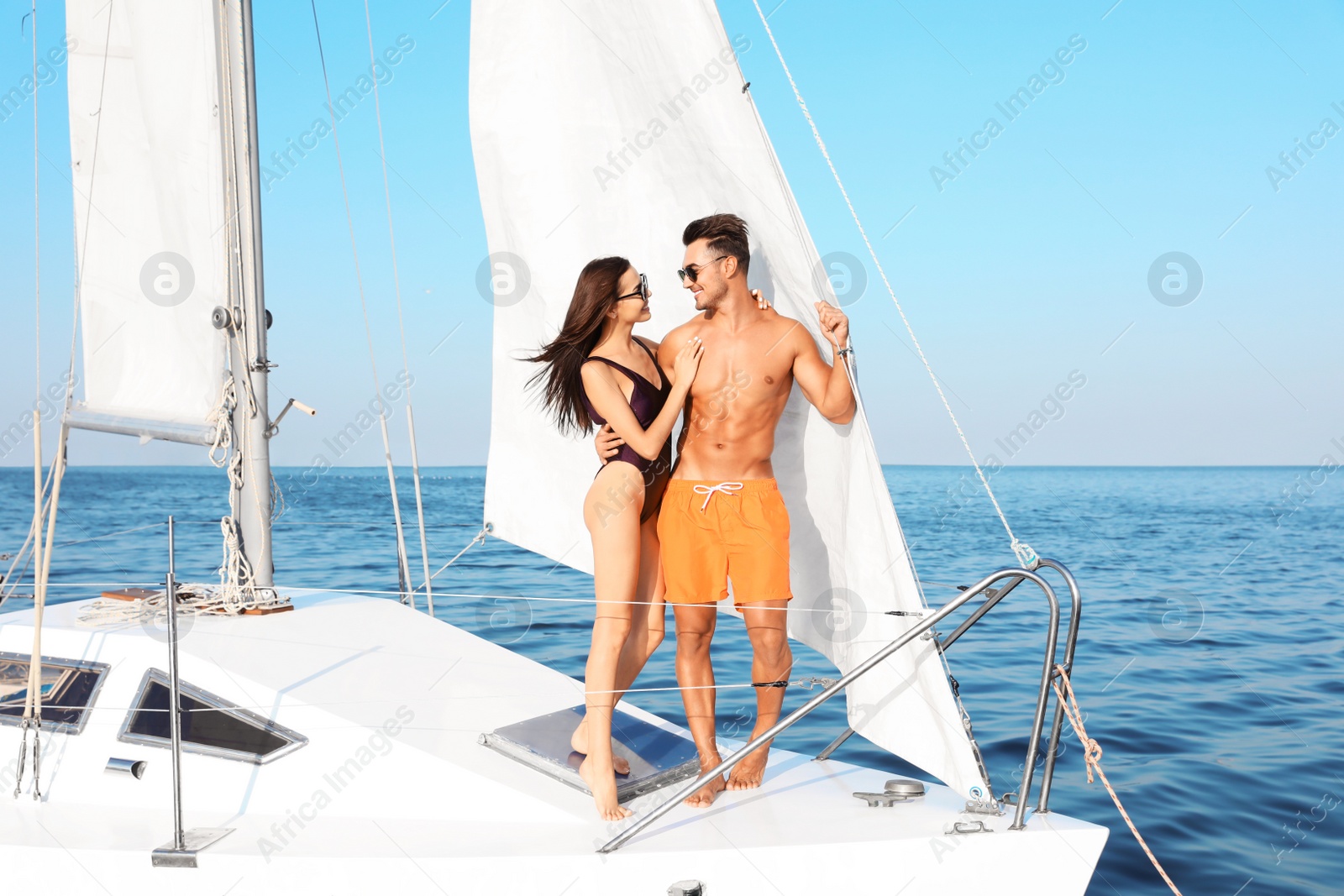 Photo of Young man and his beautiful girlfriend in bikini on yacht. Happy couple during sea trip