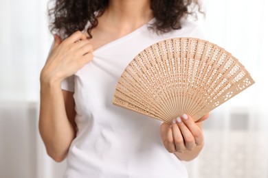 Woman with hand fan indoors, closeup view