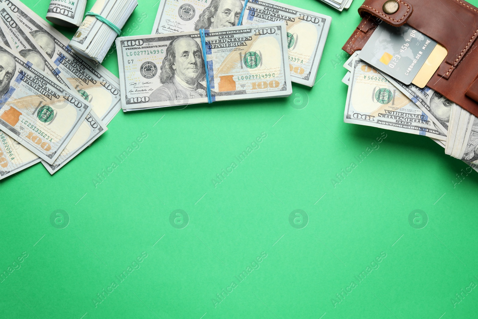 Photo of Many dollar banknotes with wallet and credit cards on green background, flat lay. Space for text